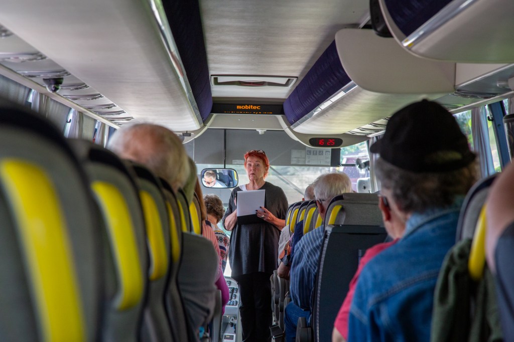 Sirpa Nurkkala-Kilpiäinen pitää bussissa nimenhuutoa.